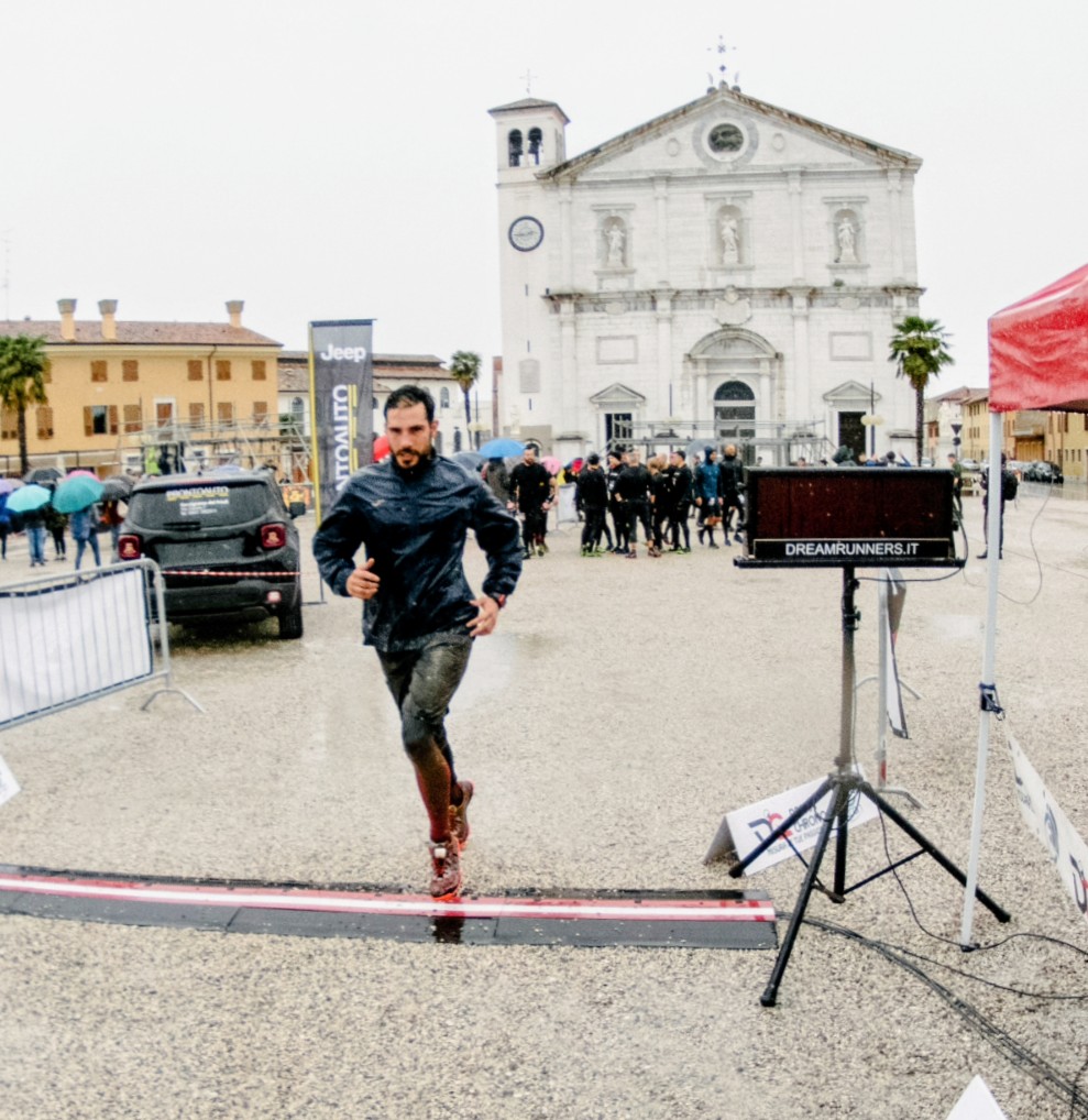 Andrea taglia il traguardo in una piazza con una chiesa sullo sfondo